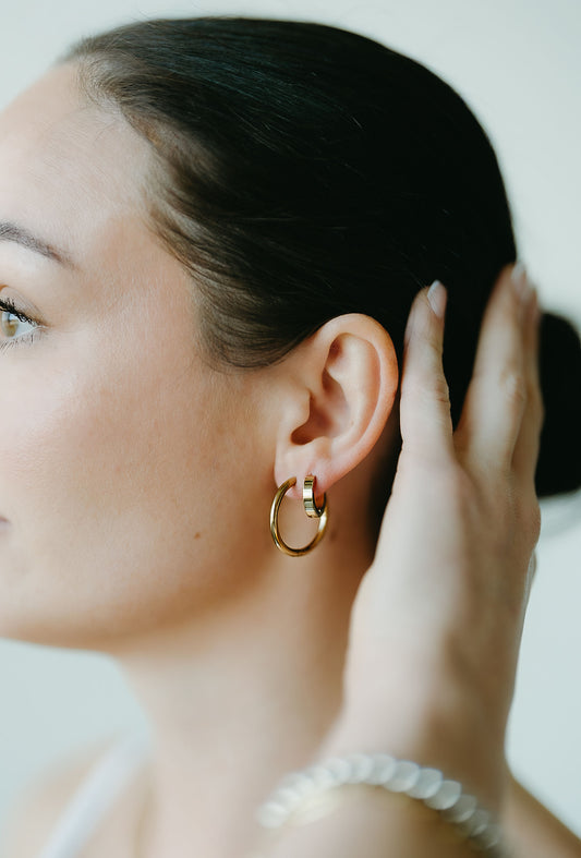 Close-up of a woman wearing a gold hoop earring with a blurred background