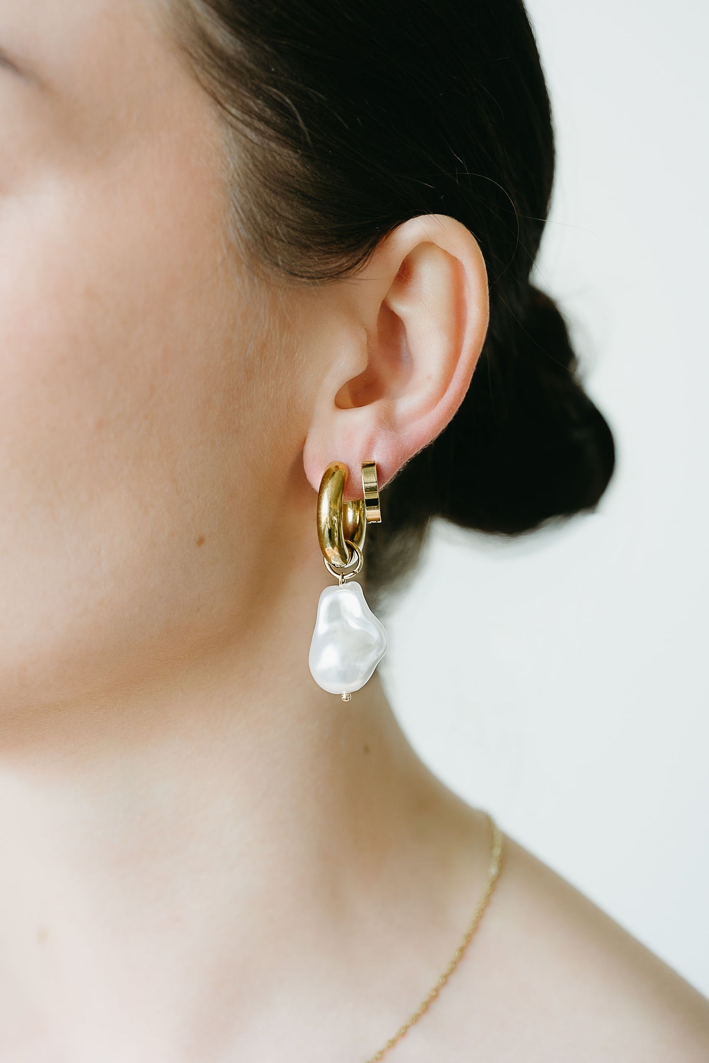 Pearl earring worn by a person with a neutral background