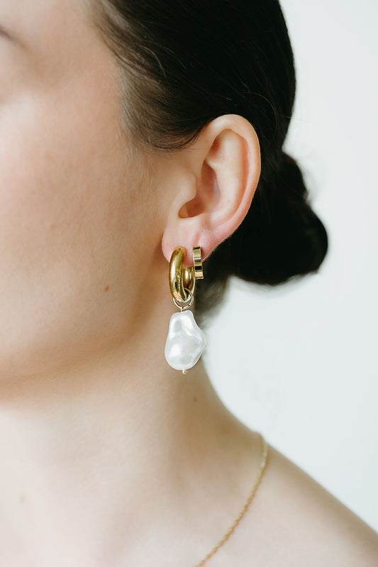 Pearl earring worn by a person with a neutral background