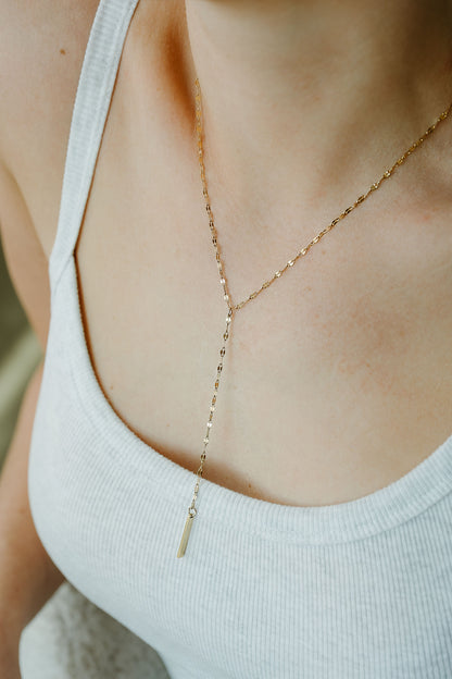 Gold necklace on a person wearing a white tank top