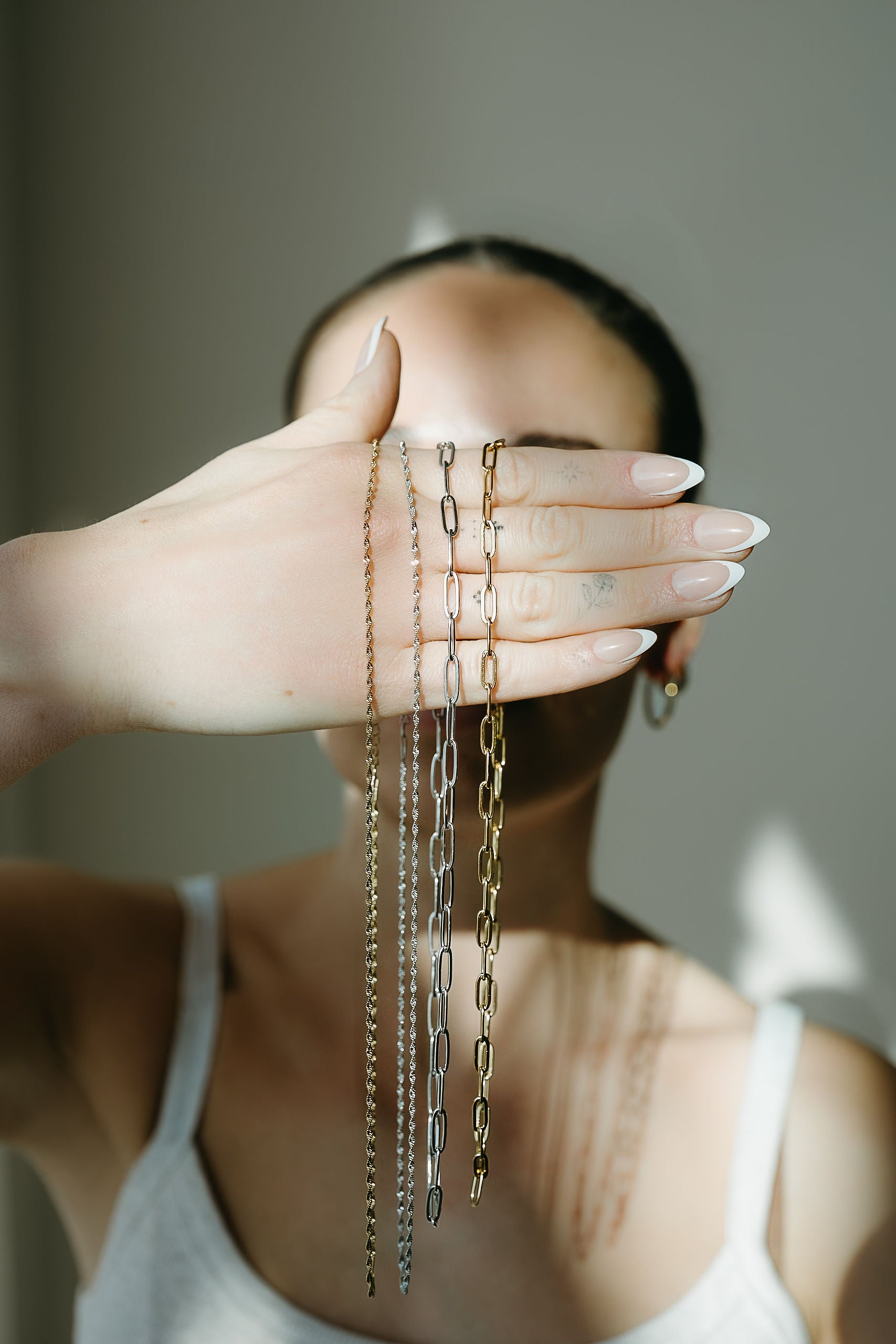 Person holding gold necklaces in front of a blurred background