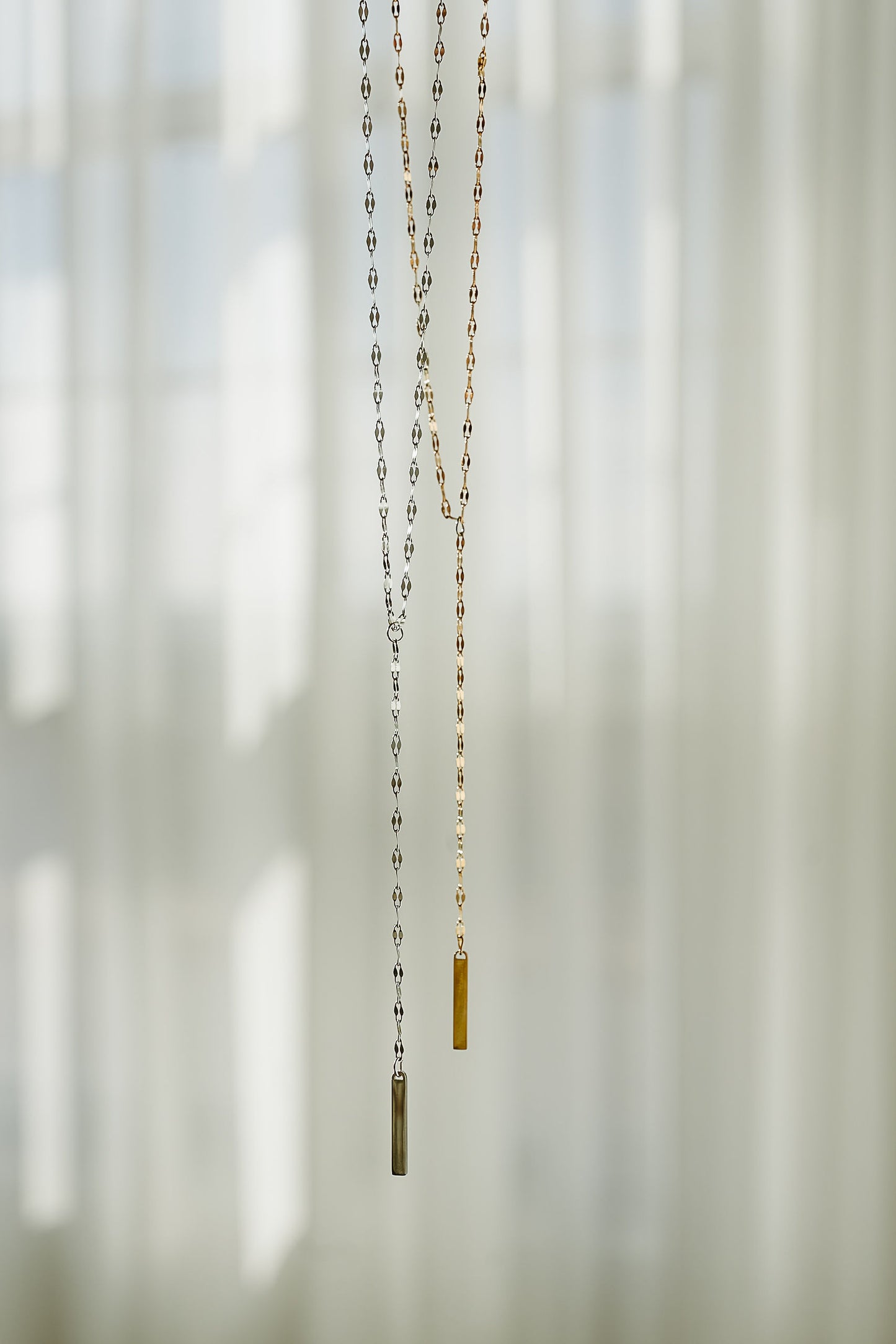 Necklace with a small pendant hanging against a blurred natural background