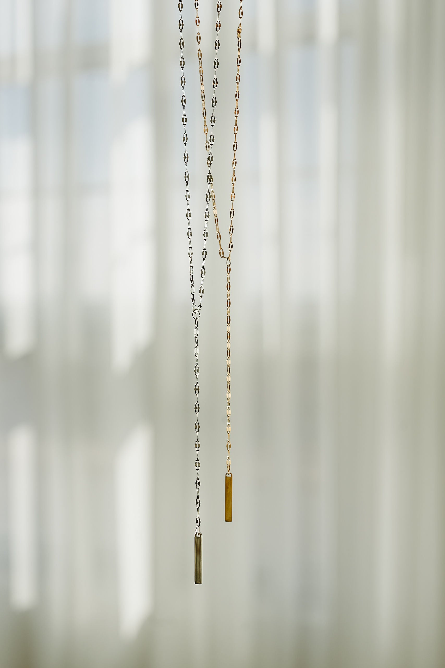 Necklace with a small pendant hanging against a blurred natural background