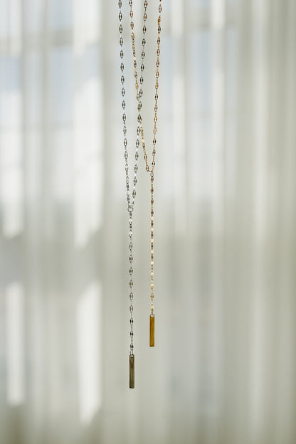 Necklace with a small pendant hanging against a blurred natural background