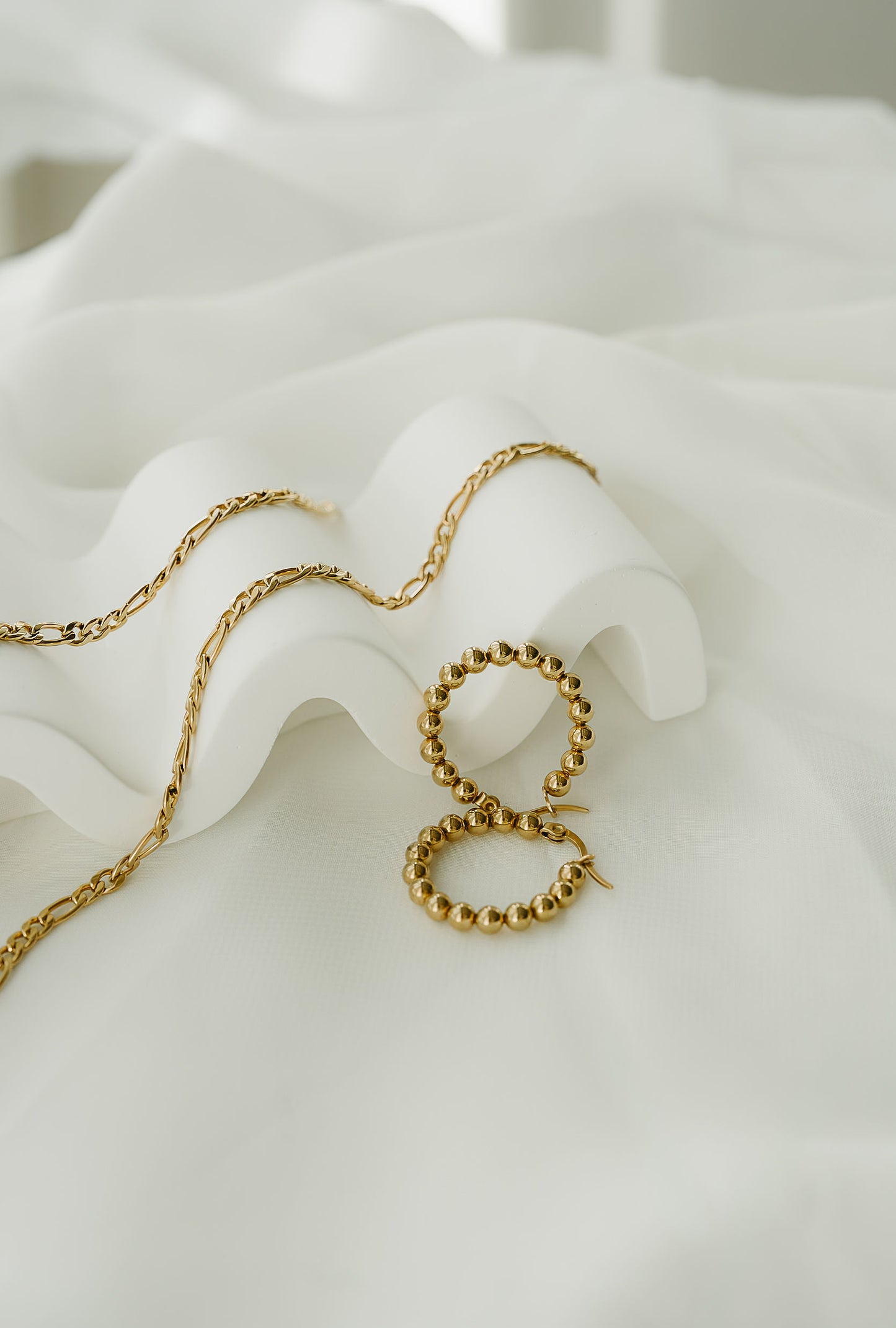 Gold chain necklace on a white textured surface